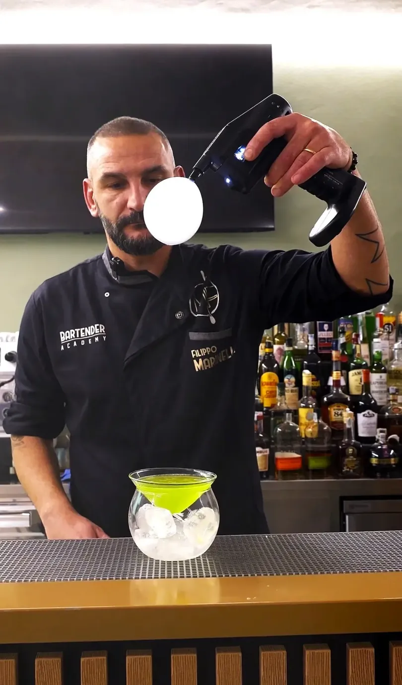 Filippo crea una bolla di fumo sopra un cocktail al bancone.